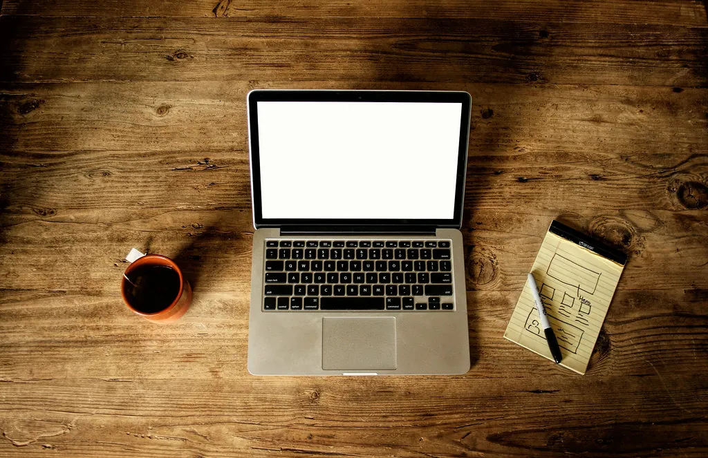 Laptop mit leerem Bildschirm und Skizzen für ein Website-Layout